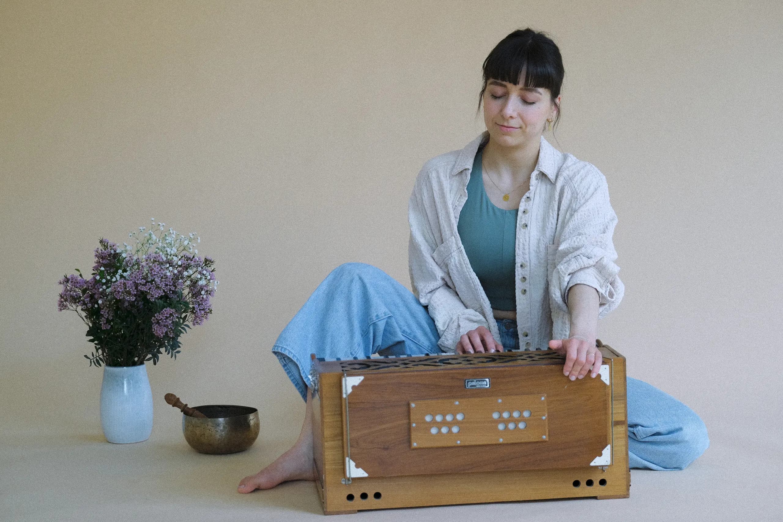 Julia spielt Harmonium, daneben Klangschale und Blumen